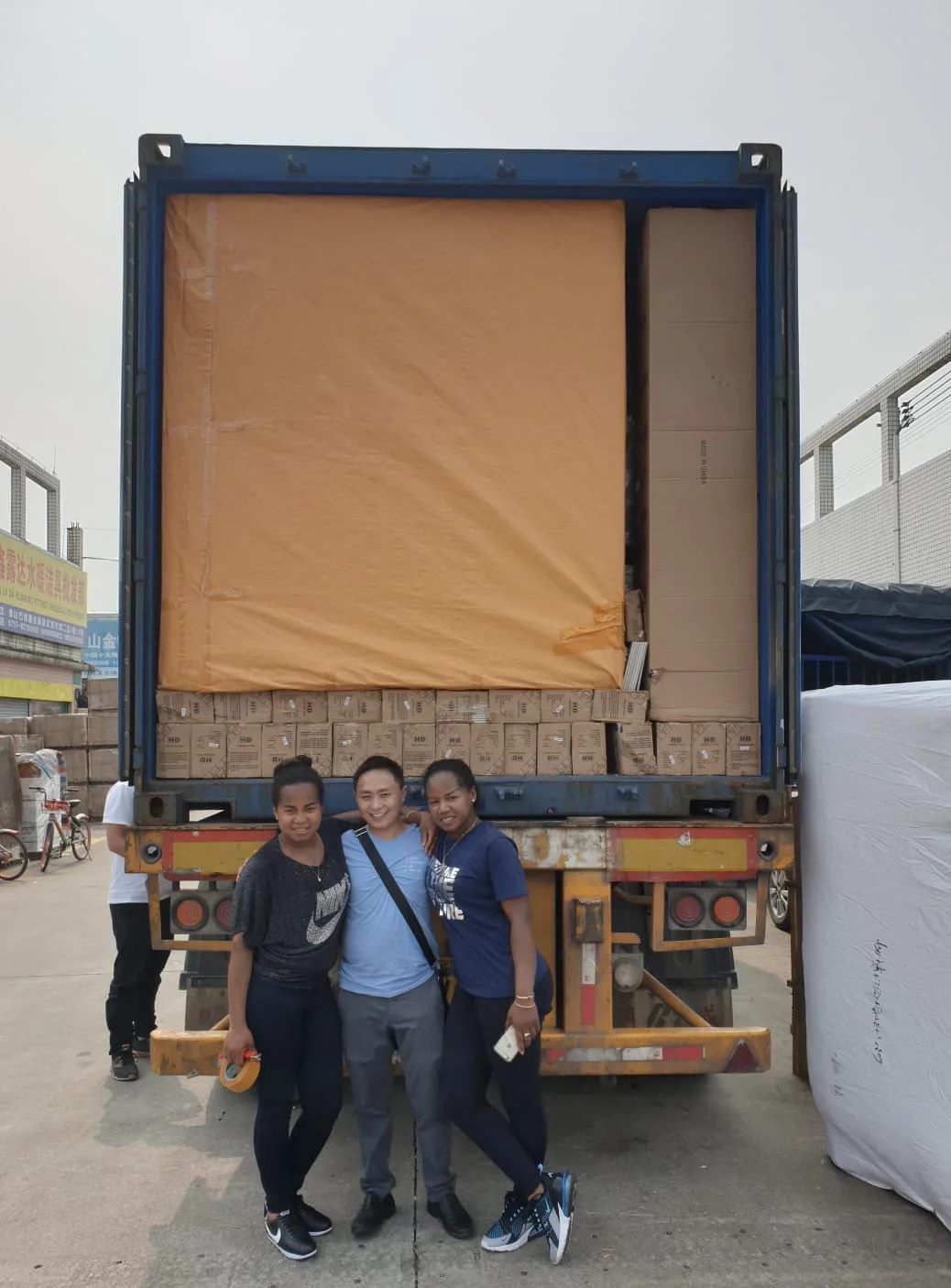 Overseas clients standing in front of a loaded furniture container in China